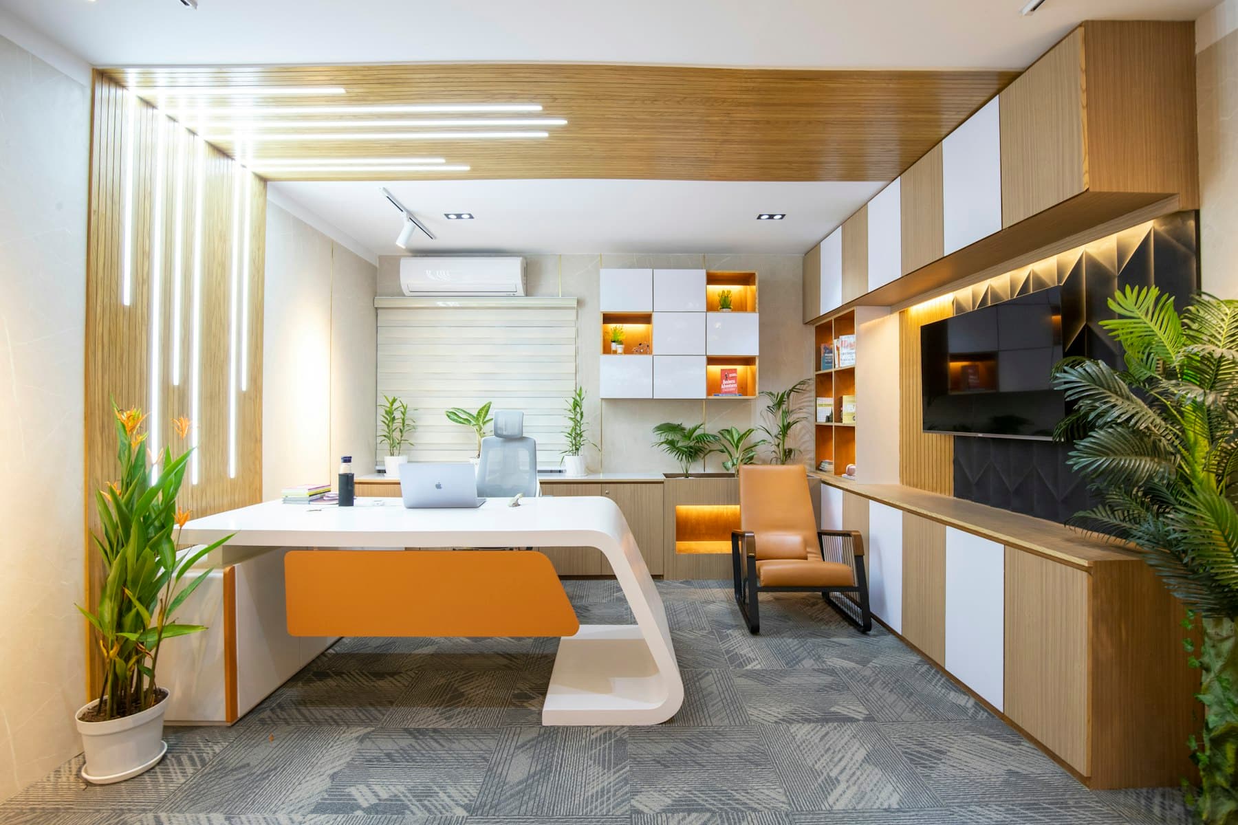 A bright office with wooden shelving, plants and a long work table